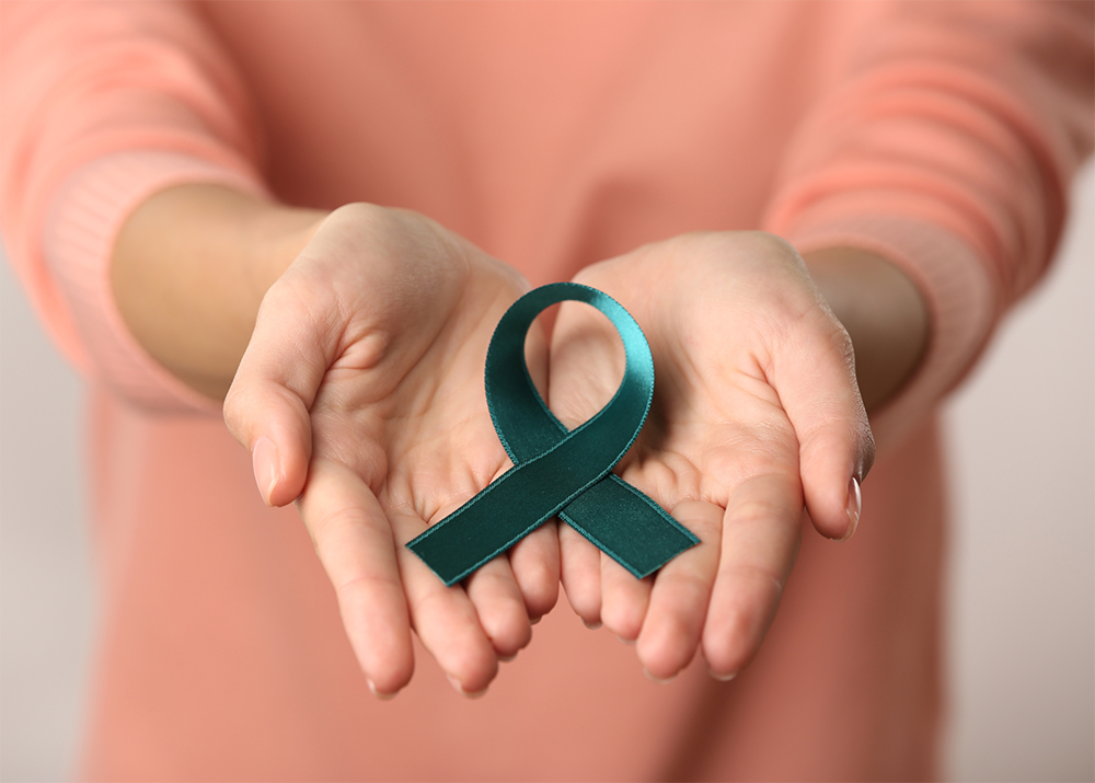 A woman’s palms held out with a teal ribbon to show support for PCOS