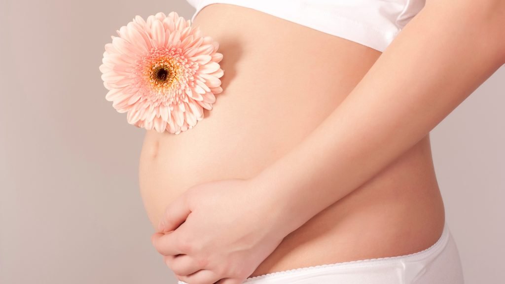 Pregnant woman with flower on belly showing egg quality